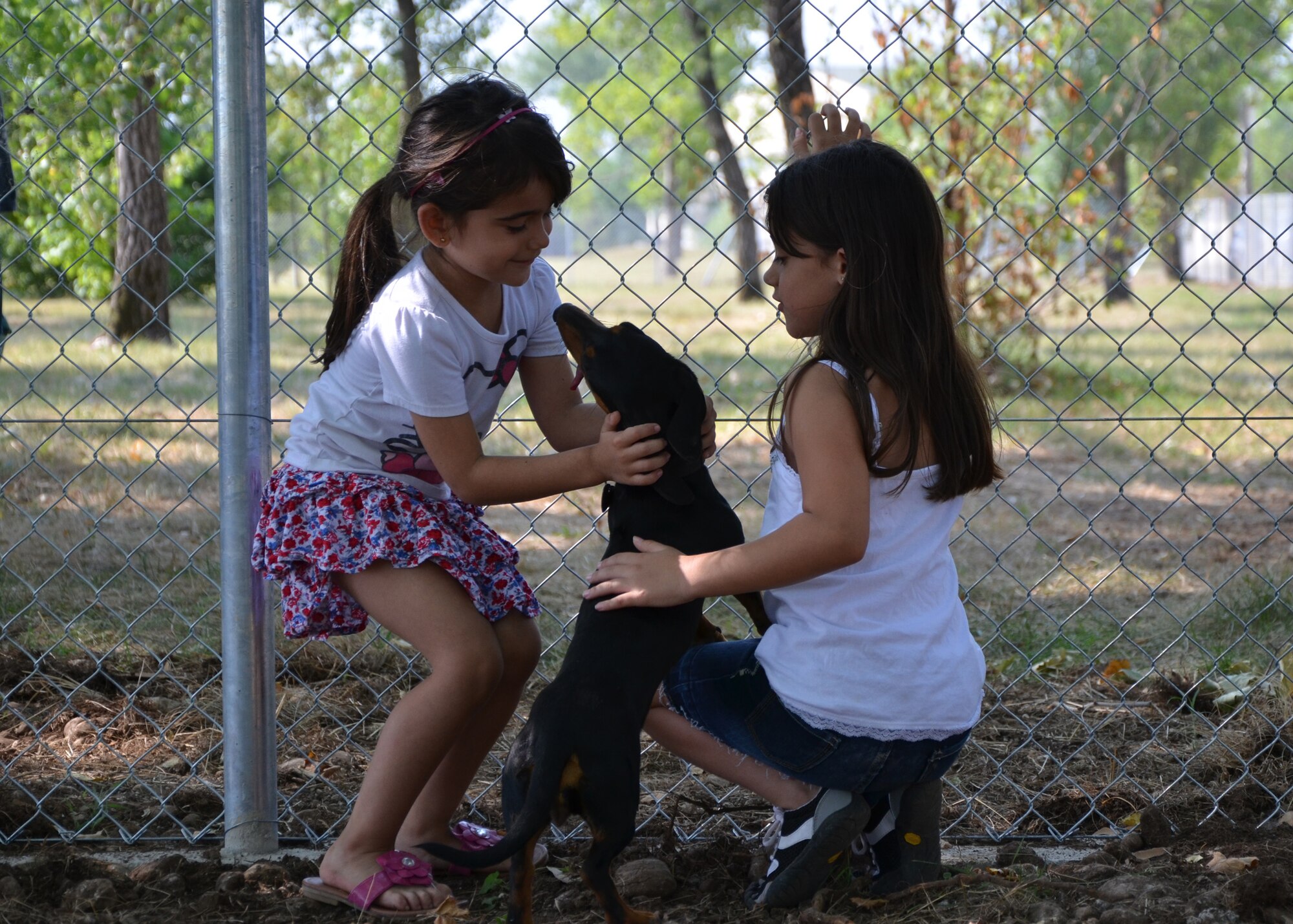 Adrianna (left) and BreAnn Dickerson play with their dog Maxie after the opening of the Aviano Dog Park July 4, 2012.  The quality-of-life initiative was put into action after requests came through town hall meetings, the interactive customer evaluation system and spouse network channels. (U.S. Air Force photo/Capt. Erick Saks)