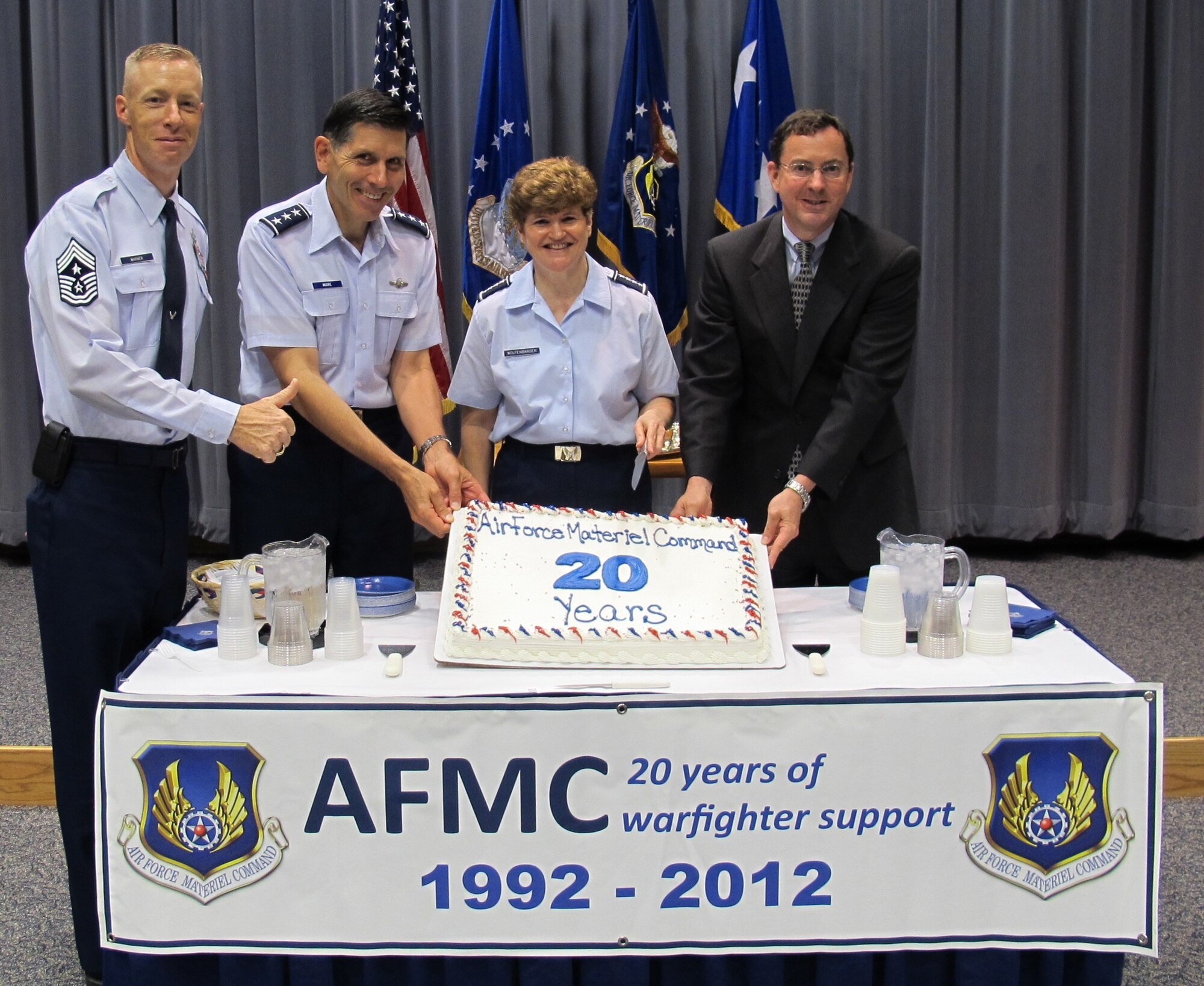 Gen. Janet Wolfenbarger, commander of Air Force Materiel Command, prepares to cut a cake to commemorate the 20th anniversary of AFMC. The brief ceremony marking the occasion took place in Headquarters AFMC July 2, 2012. The command's 20th birthday was July 1. Assisting the general are (from left) Command Chief Master Sgt. Michael Warner, Lt. Gen. C.D. Moore II, AFMC vice commander, and Dr. Steve Butler, AFMC executive director. (U.S. Air Force photo/Ron Fry)
