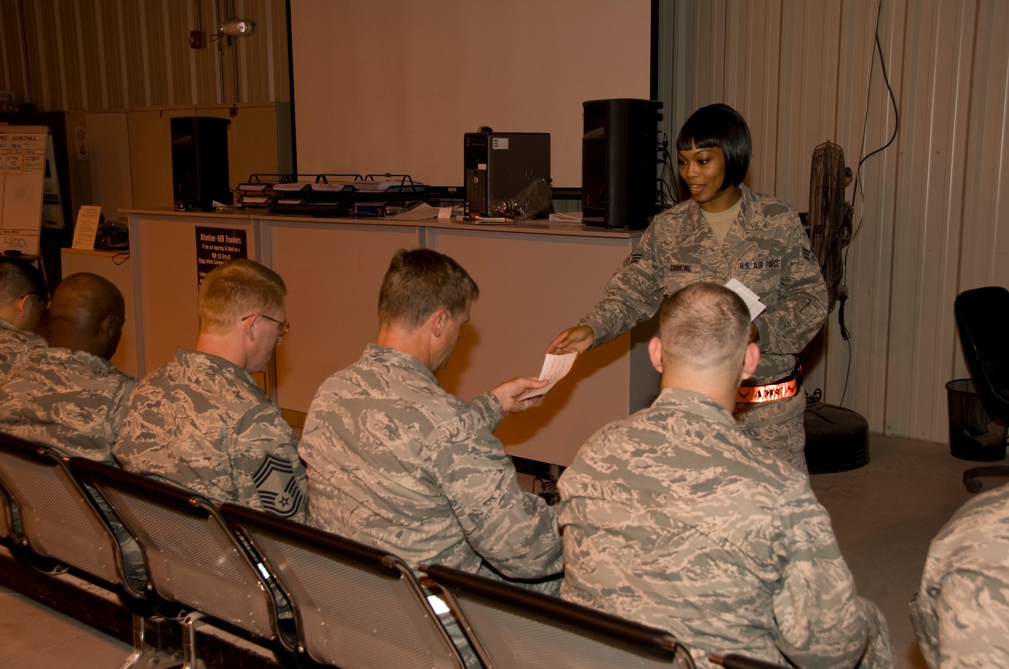 Senior Airman Chenell Simmons, 379th Expeditionary Force Support Squadron PERSCO reception control center member, passes out blank accountability sheets to service members who just landed in Southwest Asia on July 5, 2012. Accountability sheets are one of the first things service members must accomplish on arrival to ensure they are accounted for and registered into DCAPES. (U.S. Air Force photo/Senior Airman Bryan Swink)