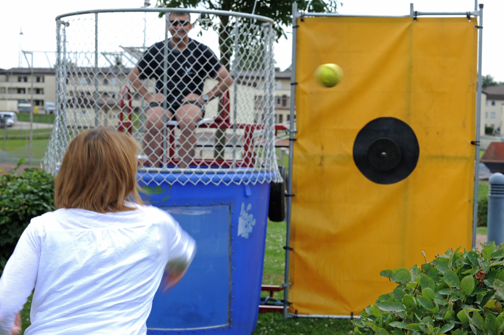 SPANGDAHLEM AIR BASE, Germany – Kate Julazadeh throws a ball to dunk her husband, Col. David Julazadeh, 52nd Fighter Wing commander, during Super Saber Appreciation Day at the base pavilion near the Eifel Lanes Bowling Center July 4. The event included a number of activities including pony rides, a carousel and swings, and two bouncy castles were available for younger children. The 52nd Force Support Squadron sponsored the event to celebrate Independence Day and show appreciation to the 52nd FW community. (U.S. Air Force photo by Senior Airman Matthew B. Fredericks/Released)