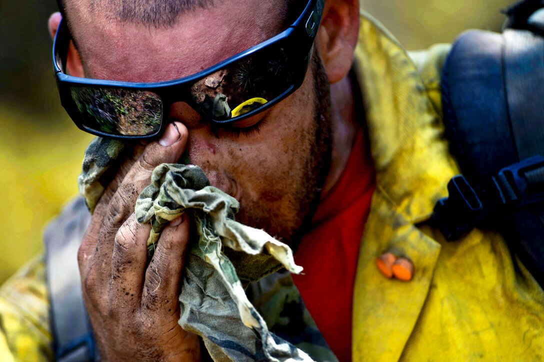 Chris Loung, a firefighter from the Hot Shots, a specialized team of firefighters from Vandenberg Air Force Base, Calif., wipes sweat from his face while cutting a fire line in the Peregrine neighborhood of Colorado Springs, Colo., June 28, 2012. 