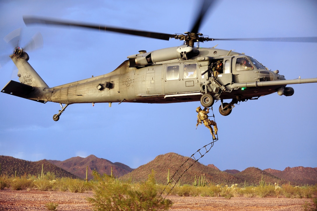 An Air Force pararescueman climbs a rope ladder back into an HH-60 Pave Hawk helicopter during a tactical training mission in Tucson, Ariz., June 27, 2012. 