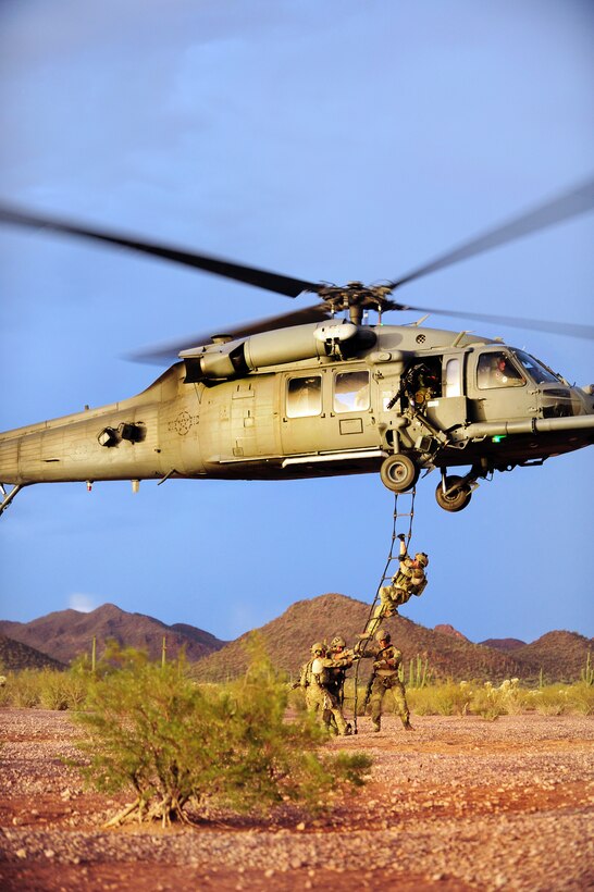 Air Force pararescuemen help each other climb a rope ladder back into an HH-60 Pave Hawk helicopter during a tactical training mission in Tucson, Ariz., June 27, 2012. 
