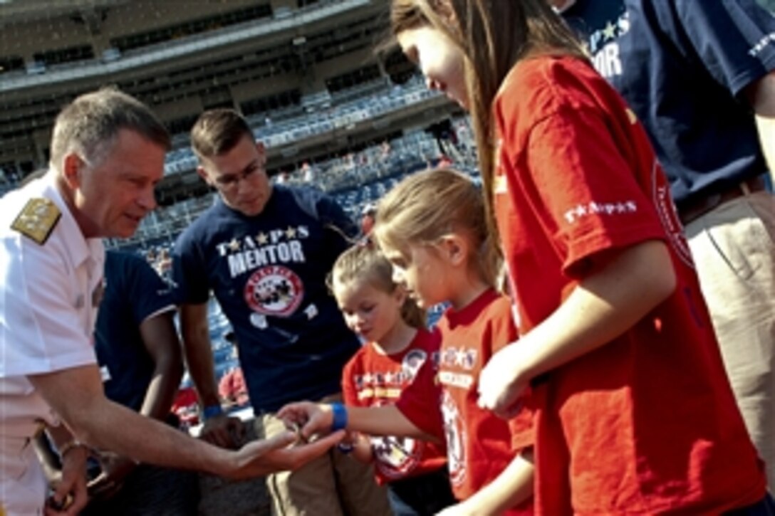 Navy Adm. James A. Winnefeld Jr., vice chairman of the Joint Chiefs of Staff, passes out coins to children from the Tragedy Assistance Program for Survivors organization at the Washington Nationals game against the San Francisco Giants in Washington, D.C., July 4, 2012. TAPS  provides peer-based emotional support, grief and trauma resources, seminars, case work assistance, and 24/7 crisis intervention care for all those affected by the death of a loved one in military service.