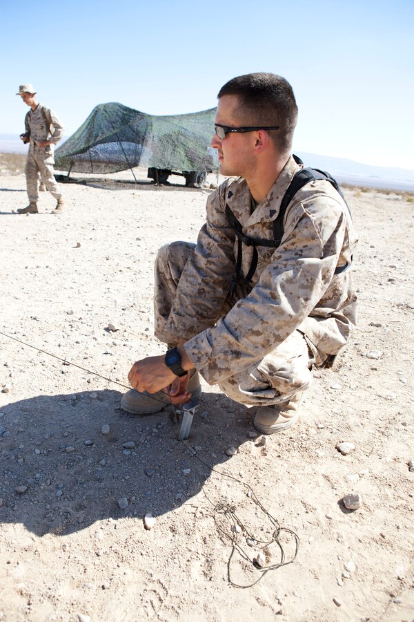 Cpl. Joshua Robie, a field wireman with 25th Marine Regiment, stakes down wire for a field expedient antenna at Range 500A during Exercise Javelin Thrust. Javelin Thrust is an annual large-scale exercise here which allows active and reserve Marines and sailors from 38 different states to train together as a seamless Marine Air Ground Task Force.