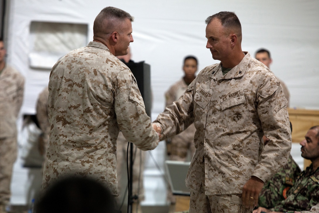 U.S. Marine Col. Roger B. Turner Jr., the commanding officer Regimental Combat Team 5, shakes hands and gives the floor to Col. John R. Shafer, the commanding officer of RCT-6, after speaking during a transfer of authority ceremony here, July 5, 2012. Since their activation in 1917, 5th and 6th Marine Regiments have courageously fought for America, most notably in World War I when they fought side-by-side in the bloody Battle of Belleau Wood. In December 2011, Regimental Combat Team 6 arrived in northern Helmand province to support Operation Enduring Freedom, joining RCT-5 on the same battlefield for the first time in 94 years. This historic partnership is now coming to a close.  Turner and Ruiz, the commanding officer and sergeant major of RCT-5, cased the colors of ‚Fighting Fifth‚ and transferred authority of their area of operations to Shafer and Sgt. Maj. Jamie Deets, the sergeant major of RCT-6 here, July 5.