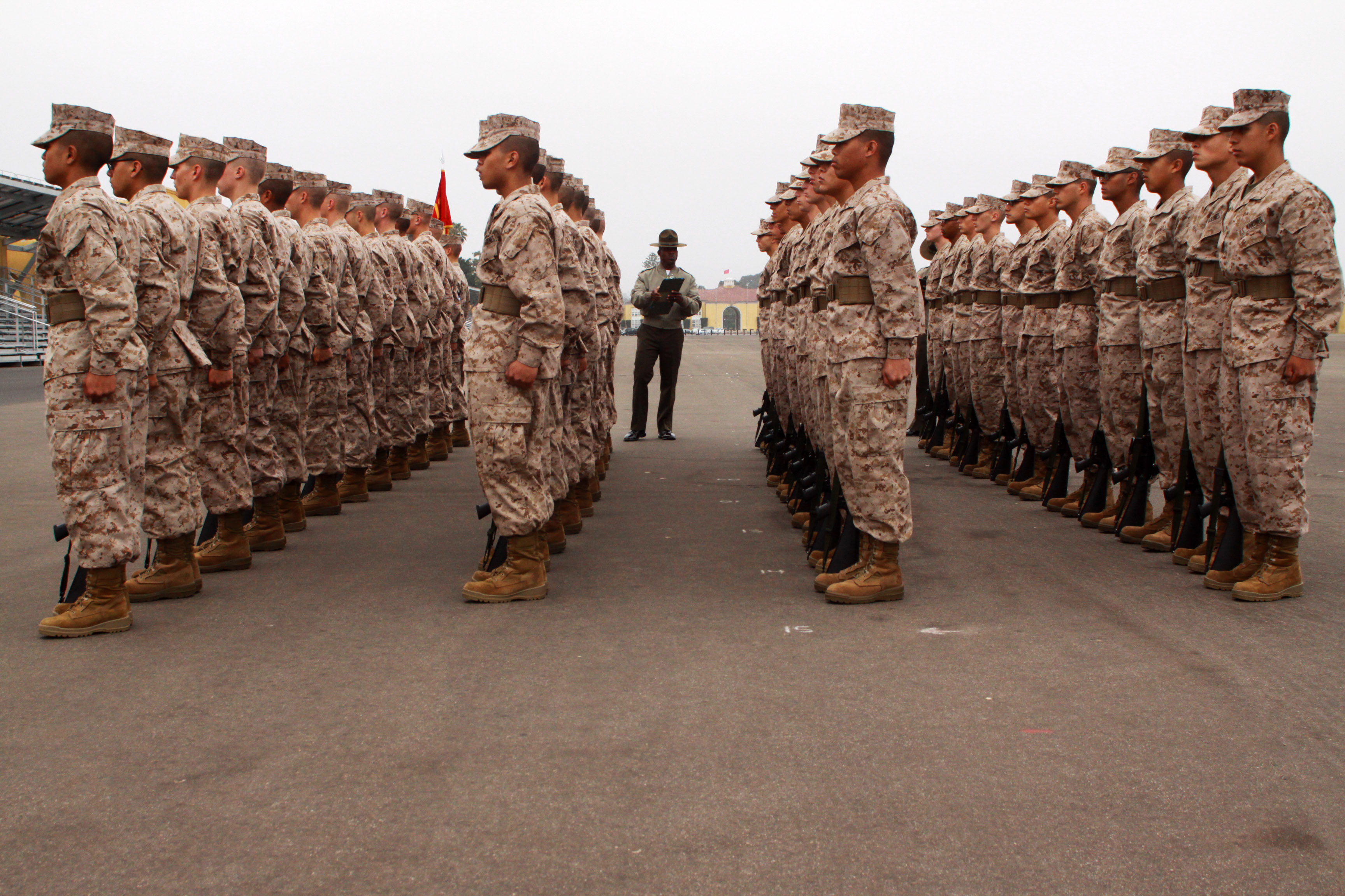 Recruits with Platoon 3273, Company M, 3rd Recruit Training Battalion stand at the position of attention while drill masters evaluate the platoon during a final drill competition aboard Marine Corps Recruit Depot San Diego June 18. Recruits are taught the basic fundamentals of drill and are graded during final drill based on how well they perform each movement. Drill instills discipline in recruits and instant obediance to orders.