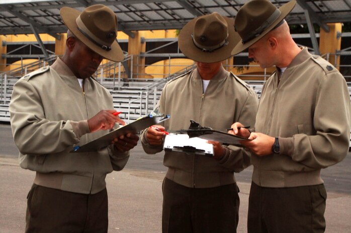 Drill masters with 3rd Recruit Training Battalion calculate their scores after judging a platoon during a final drill competition aboard Marine Corps Recruit Depot San Diego June 18. The drill masters scored the platoons with Company M on how well they performed drill movements and the proper wear of their uniform.