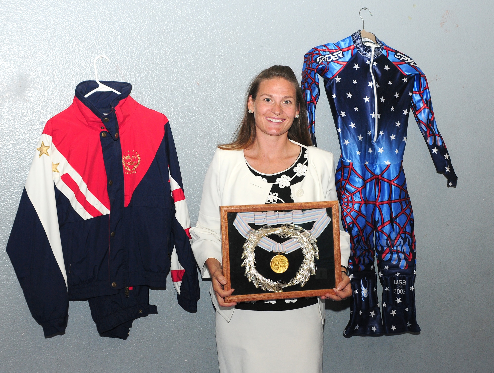 Jennifer Kelchner, a Paralympics gold medalist poses for a photo with her gold medal and her Olympic uniforms at the Youth Center at Beale Air Force Base, Calif., June 27, 2012. Kelchner also won the bronze medal for the slalom skiing event at the 2002 Winter Olympics in Salt Lake City, Utah. (U.S. Air Force photo by Senior Airman Allen Pollard)