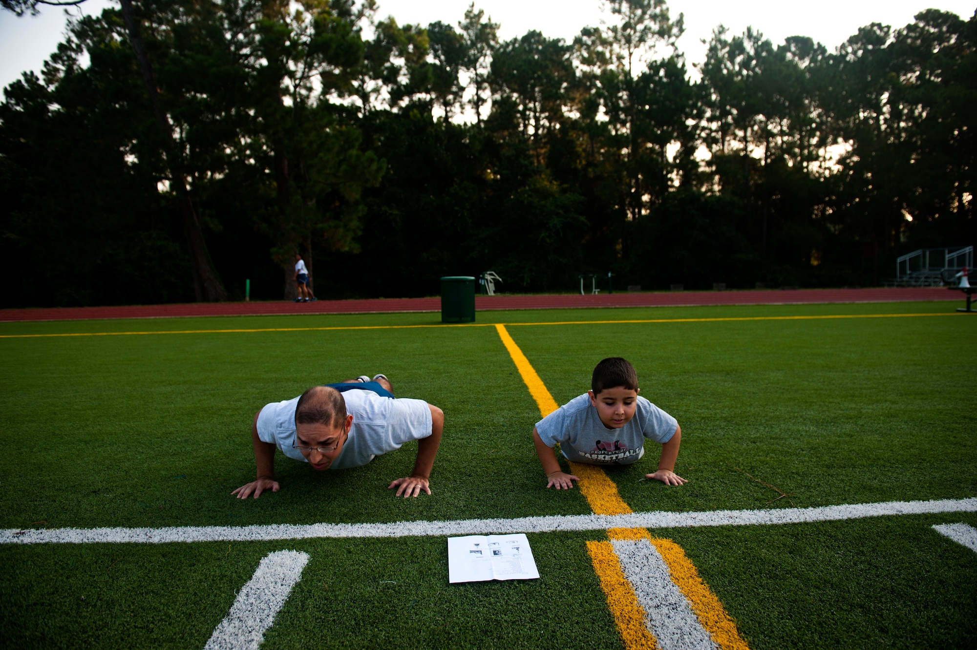 From left, Senior Master Sgt. Manuel Martinez, Air Force Special Operations Command A1 office, leads group physical training with his son, Alessandro, 7, June 29, 2012, at Hurlburt Field, Fla. AFSOC hosted a Bring Your Child to Work Day. (U.S. Air Force photo by Staff Sgt. David Salanitri) 