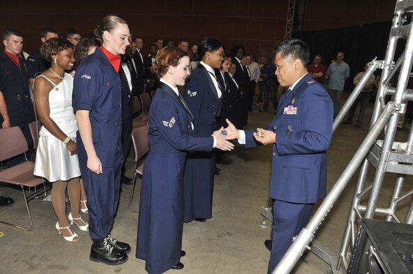 Col. H.B. Brual, 341st Missile Wing commander, right, coins the members of the 2012 Tops In Blue tour following their performance June 27.  Brual opened their ceremony by thanking the service and community members in attendance and acknowledging the talent of the performers. (U.S. Air Force photo/John Turner)