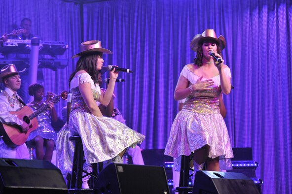 Capt. Ashley Elmore, 28th Force Support Squadron officer; Ellsworth AFB, S.D., left; as the main singer and Staff Sgt. Robin Elrod 303rd Intelligence Squadron cryptologic language operator; Osan Air Base, Republic of Korea; sing “Mama’s Song” by Carrie Underwood with help from other Tops In Blue members in the background. (U.S. Air Force photo/John Turner)