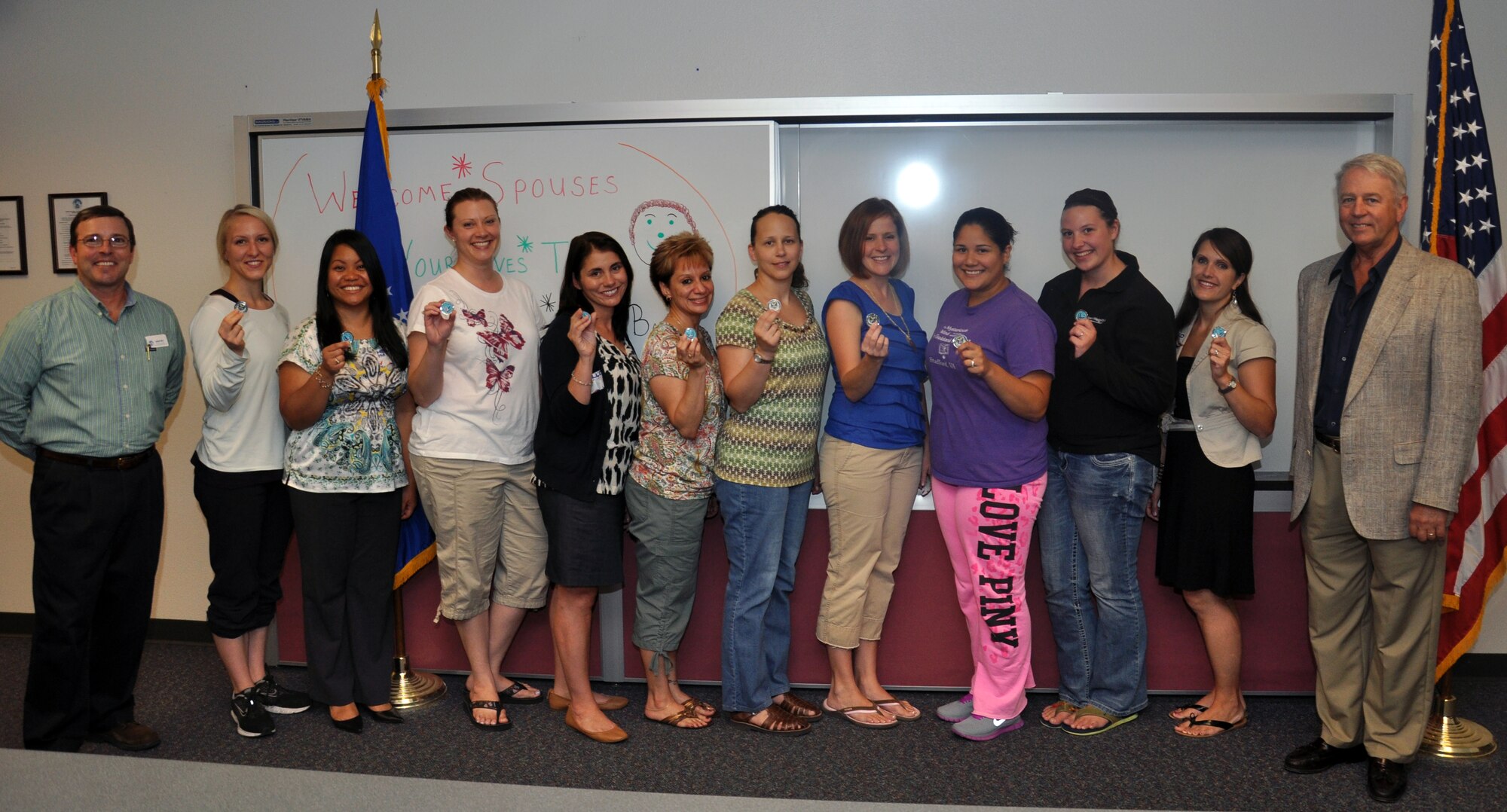 Jim Headstream, 90th Force Support Squadron Airman and Family Readiness Center Director, and Ron Navarra, 90th FSS, pose for a photo with attendees of the Warren Spouses Tour June 28 in the Airman and Family Readiness Center. The tour attendees are displaying HeartLink coins presented to them at the conclusion of the Spouses Tour. During the tour attendees learned about services offered on base through visits to the Base Exchange and Commissary; Health and Wellness Center; Outdoor Recreation; lunch at the Chadwell Dining Facility; 90th Medical Group clinic; Youth Center; Community Center; and the Arts and Crafts Center. (U.S. Air Force photo by Senior Airman Dan Gage)