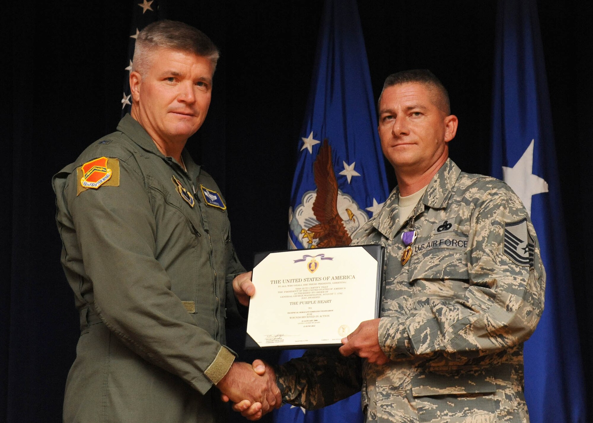 Brig. Gen. JD Harris, 56th Fighter Wing commander, presents the Purple Heart June 29 to Master Sgt. Jordan Velissariou, 56th Logistics Readiness Squadron vehicle fleet manager at Luke Air Force Base. While deployed to Iraq in 2006, Velissarious’ femoral artery was crushed after a series of attacks on his truck during a convoy.  (U.S. Air Force photo by Staff Sgt. Darlene Seltmann)