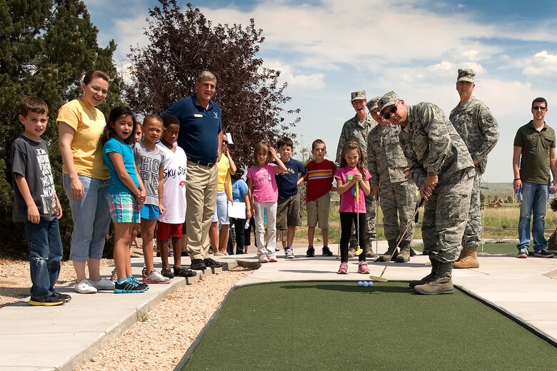 The crowd looks on as Col. Chris Crawford, 21st Space Wing commander, makes the first putt on the new Peterson mini-golf course located in Peak View Park, across from the Peterson Base Exchange. The grand opening for the nine-hole course was July 3. (U.S. Air Force photo/Craig Denton)