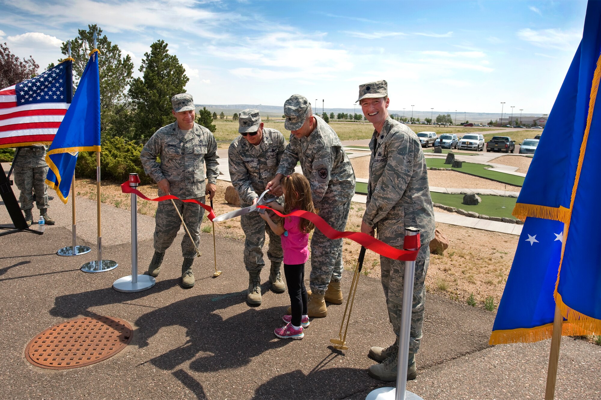 Col. Chris Crawford (center), 21st Space Wing commander; Command Sgt. Maj. Robert A. Winzenried (center right), command senior enlisted leader, North American Aerospace Defense Command and United States Northern Command;  and Camryn Nastiuk (center), daughter of Liz Nastiuk, 4th Manpower Requirements Squadron; cut a ribbon at the grand-opening of the new Peterson mini-golf course located in Peak View Park, across from the Peterson Base Exchange July 3. Col. Charles Arnold (left), 21st Mission Support Group commander, and Lt. Col. Ann M. Igl (right), 21st Force Support Squadron commander, hold special gold putters for use on the new course. (U.S. Air Force photo/Craig Denton)
