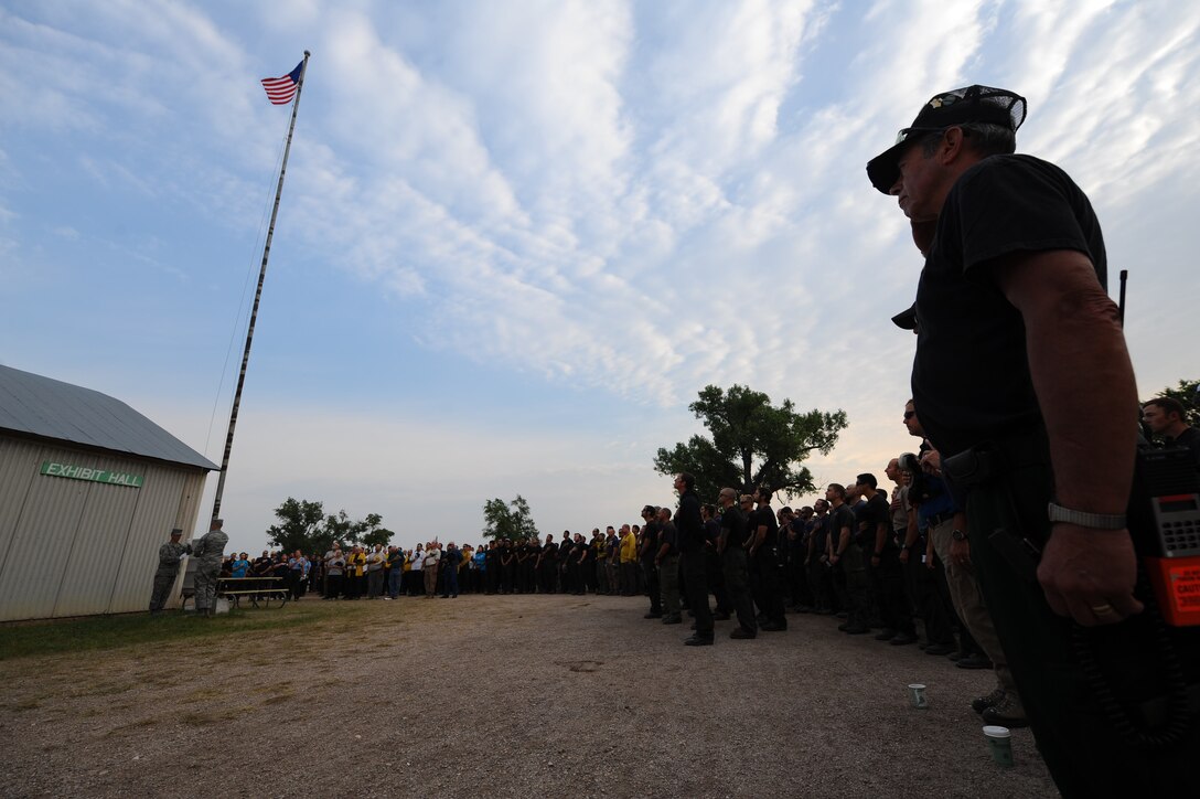 Firefighters watch as Ellsworth Air Force Base Honor Guard members raise a flag dedicated to the fallen Airmen who gave their lives in the C-130 accident while battling the White Draw wild fire in southwest South Dakota, during a memorial service at Edgemont, S.D., June 5, 2012. (U.S. Air Force photo by Airman 1st Class Zachary Hada/Released)