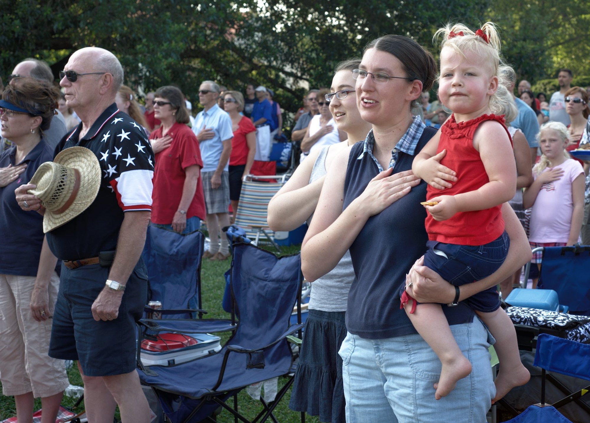 Audience members, including Elaine Warner, 2, hold their hands over their hearts while the U.S. Air Force Heritage of America Concert Band plays the National Anthem at Williamsburg, Va., July 4, 2012. In addition to entertaining and inspiring onlookers, the band served as a tool to allow for interaction between the Air Force and the public. (U.S. Air Force photo by Tech. Sgt. Barry Loo/Released)