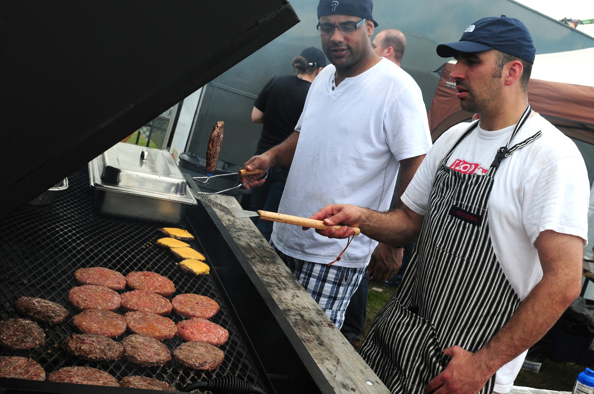 ROYAL AIR FORCE FELTWELL, England – Staff Sgt. Theodore Burley and Tech Sgt. Michael Christiansen, 100th Security Forces Squadron members, grill burgers during the Independence Day celebration here July 4, 2012. Approximately 30,000 Airmen, civilians and U.K. residents attended the event. The celebration included carnival games, rides, aerial demonstrations, a birds of prey demonstration and an Idols World Tour performance. (U.S. Air Force by Airman 1st Class Cory D. Payne)