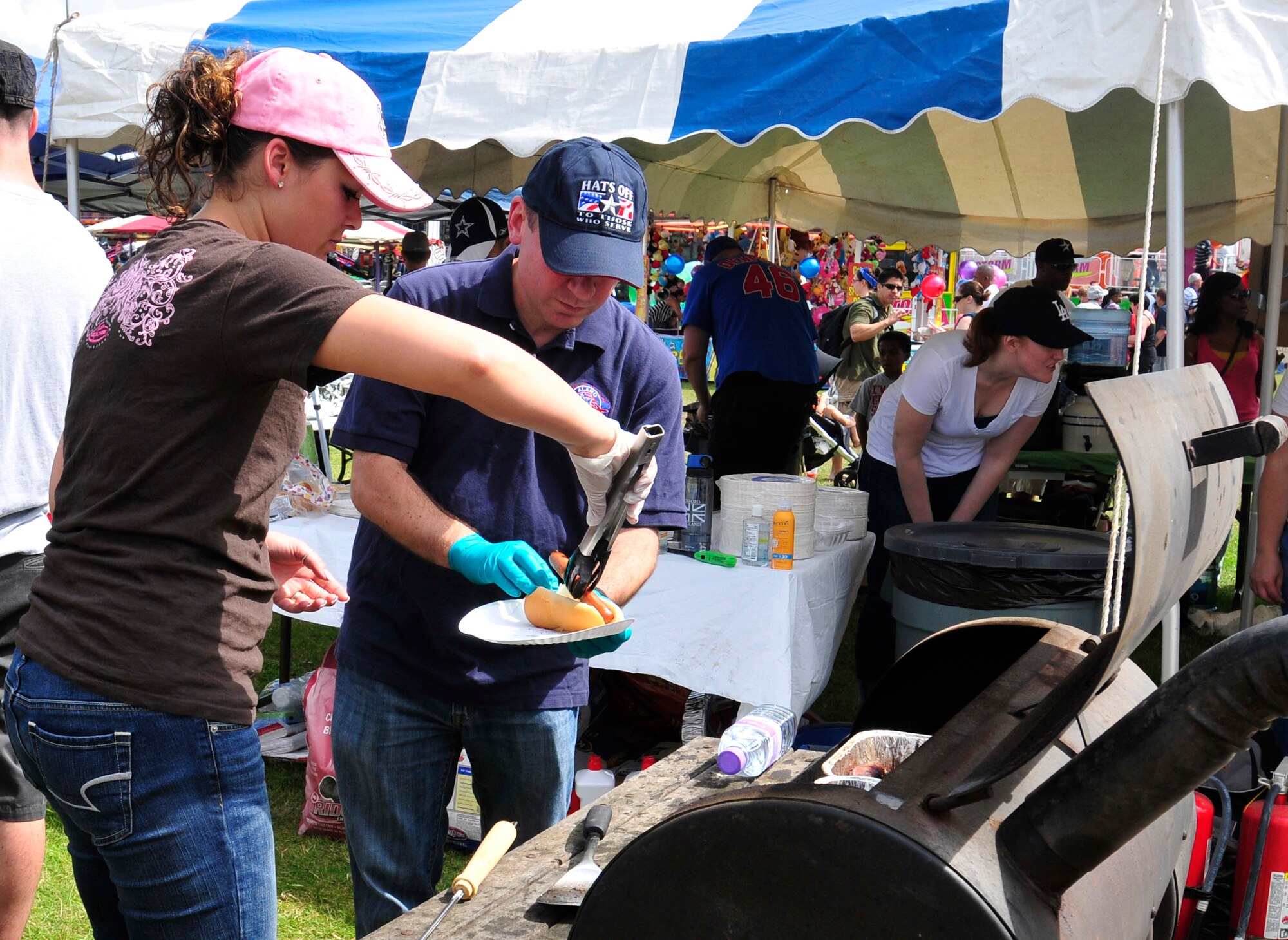 ROYAL AIR FORCE FELTWELL, England – Senior Airman Tyskanay Schofield, Detachment 4 18th Intelligence Squadron systems analyst, places a hot dog on a plate held by Tech. Sgt. Larry Moore, Detachment 4 18th IS operations superintendent, during the Independence Day celebration here July 4, 2012. Approximately 30,000 Airmen, civilians and U.K. residents attended the event. The celebration included carnival games, rides, aerial demonstrations, a birds of prey demonstration and an Idols World Tour performance. (U.S. Air Force by Senior Airman Tiffany M. Deuel)