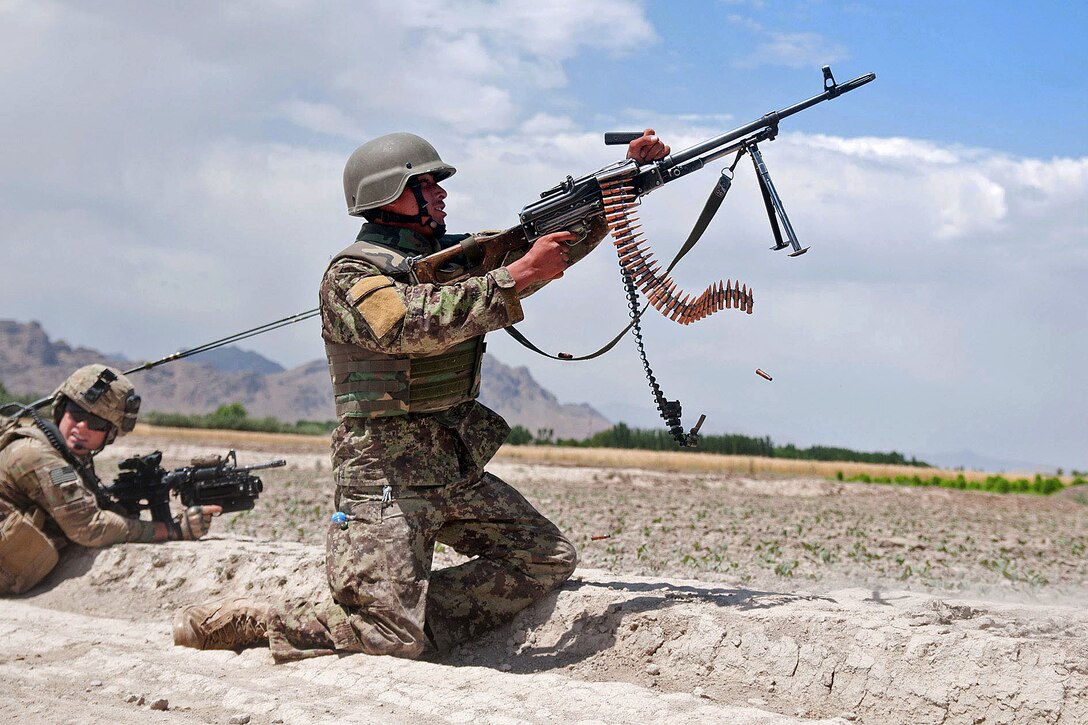 An Afghan soldier provides suppressive fire during a firefight with insurgents outside the town of Muqor in Afghanistan's Ghazni province, June 30, 2012.