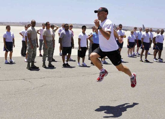 Ian Adamson, director of research and education, Newton Running, demonstrates a running drill, where runners lunge into the air as they run. It was one of many drills taught to help increase an individual’s ability to run more efficiently during the second running clinic hosted by March FITT, inside and outside Hangar 452, June 23. The first running clinic, held last June, was such a success that Adamson was invited back to continue helping Airmen improve their running techniques and extending their running life. (U.S. Air Force photo by/ Staff Sgt. Megan Crusher)