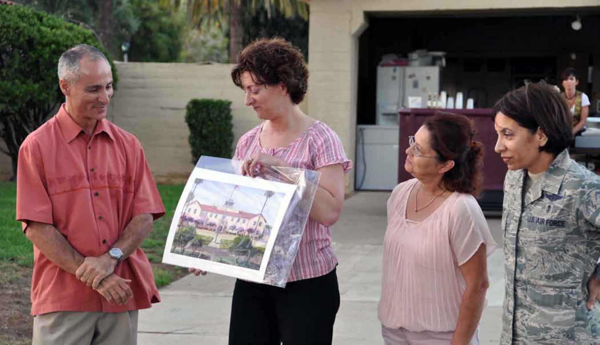 Maj. Tina Tsui presents a lithograph of the 452d Air Mobility Wing headquarters building, currently under renovation, to Brig. Gen. Karl McGregor, commander, at his farewell get-together June 23, while Elaine Plein, protocol officer and Chief Master Sgt. Ericka Kelly, command chief, look on. McGregor begins his new assignment at the
Pentagon after July 15. (U.S. Air Force photo by Lt Col Don Traud)