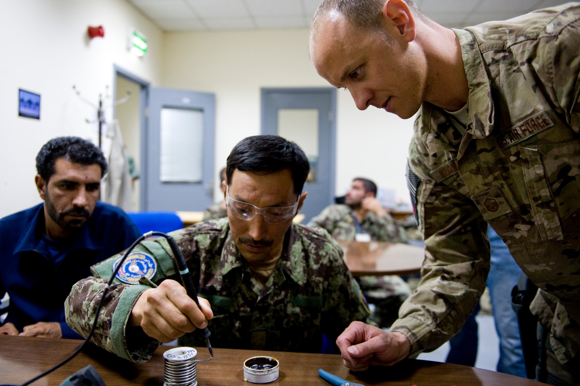 U.S. Air Force Master Sgt. Jamie Kuranda, a C-27A maintenance advisor with the 440th Air Expeditionary Advisory Squadron, wathes an Afghan air force electronic and avionics student solder a piece of wire, in Kabul, Afghanistan on July 7, 2012. The mission of the 440th AEAS is to train, mentor and advise Afghan air force Kabul Air Wing members capable of sustaining a healthy fleet that is ready to perform training and operational missions in support of Afghan national security requirements today and in the future. (U.S. Air Force photo by Staff Sgt. Greg C. Biondo)(Released)