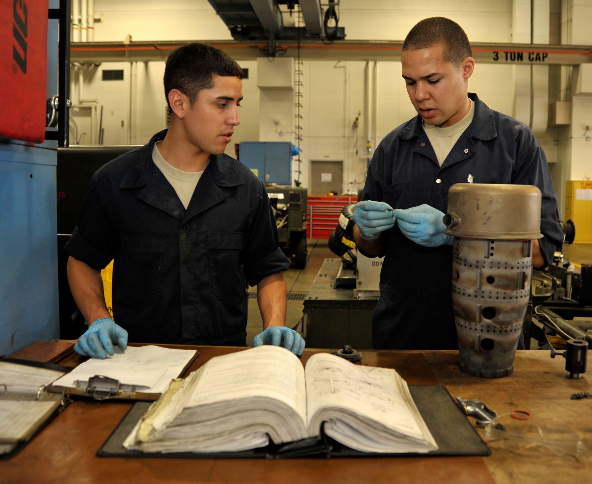 U.S. Air Force Airman 1st Class John Ortiz, left, 35th Maintenance Squadron aerospace ground equipment apprentice, learns how to perform an annual inspection on a turbine engine combustor can from Staff Sgt. Lisvaldo Liz, right, 35 MXS AGE craftsman, at Misawa Air Base, Japan, July 9, 2012. The AGE flight is responsible for maintaining the equipment that supplies electricity, as well as hydraulic and air pressure to planes as they receive maintenance and prepare for flight. (U.S. Air Force photo by Staff Sgt. Nathan Lipscomb/Released) 