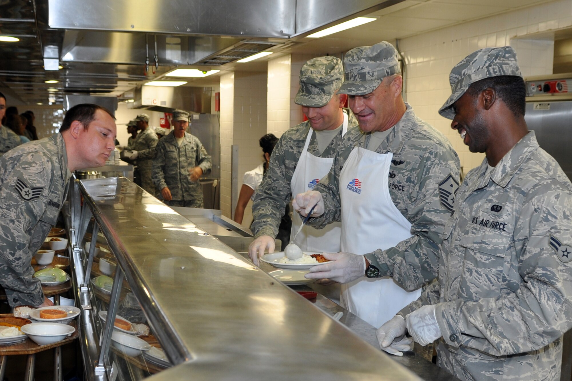 Master Sergeants Frank Kuba and Darryl Moore (L to R with aprons) serve up hot meals at the dining facility on Barksdale Air Force Base, La., July 8, 2012. Both first sergeants are assigned to the 307th Bomb Wing and were serving Barksdale Airmen to promote esprit de corps. Kuba is the first sergeant for the 307th Logistics Readiness Squadron, and Moore is the first sergeant for the 307th Mission Support Group. (U.S. Air Force photo by Master Sgt. Jeff Walston)   