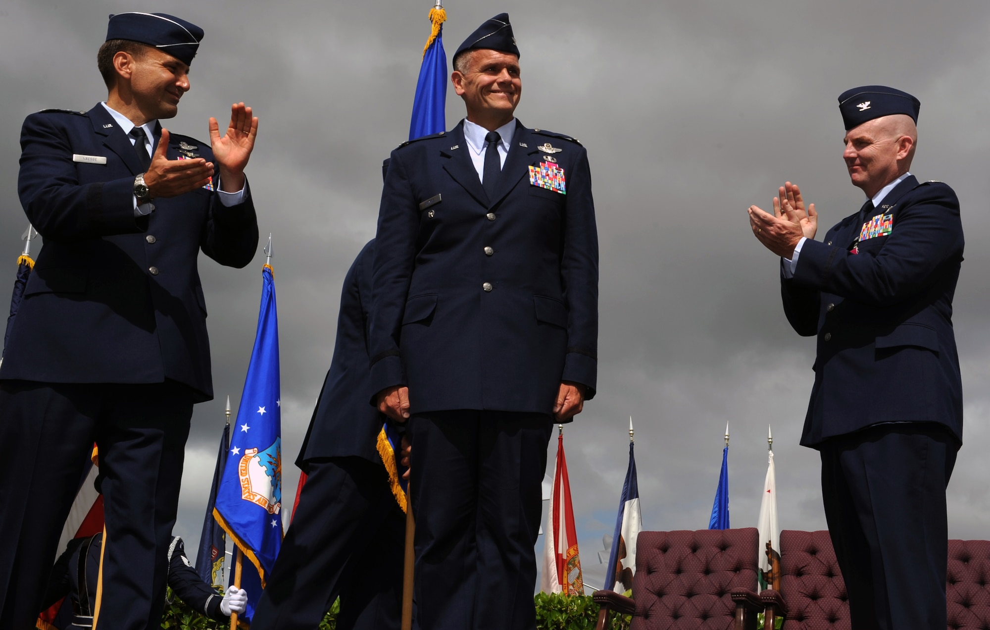 Lt. Gen. Ted Kresge, 13th Air Force commander (left), and Col. Sam Barrett, outgoing 15th Wing commander, applaud Col. Johnny Roscoe, incoming 15th WG commander, upon his assumption of command during the start of the 15th Wing Change of Command ceremony July 6 at Joint Base Pearl Harbor-Hickam, Hawaii. During the ceremony, command of the 15th WG passed from Barrett to Roscoe. (U.S. Air Force photo by Staff Sgt. Nathan Allen)