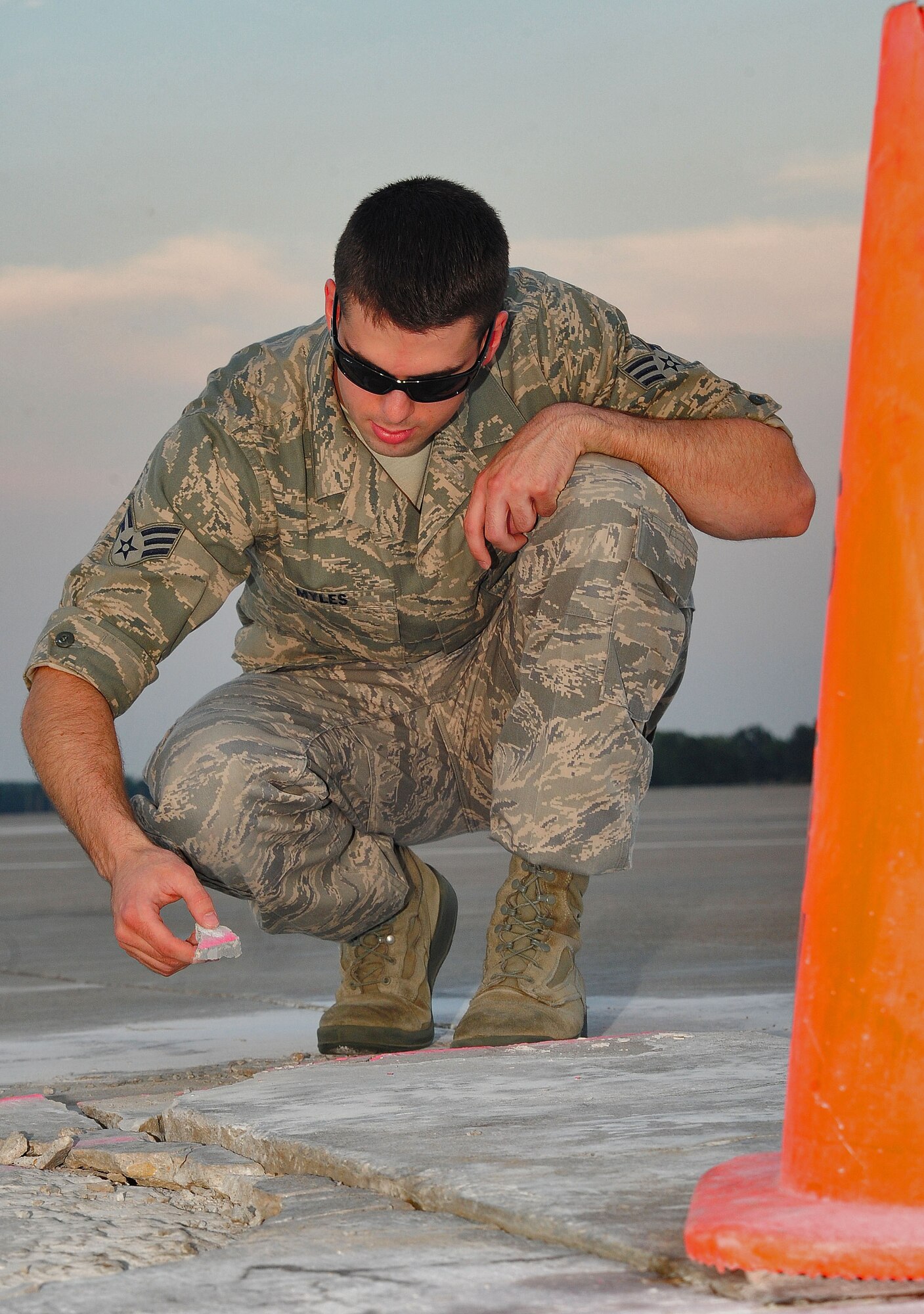 WHITEMAN AIR FORCE BASE, Mo. -- Senior Airman Dennis Myles, 509th Operations Support Squadron airfield management shift lead, collects loose pieces of concrete from the flightline as part of an inspection for items that could cause foreign-object damage June 30. Myles works with a team of airfield managers who are responsible for ensuring the safety of operations on the flightline. (U.S. Air Force photo/Senior Airman Nick Wilson) (Released)
