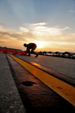 WHITEMAN AIR FORCE BASE, Mo. -- Senior Airman Dennis Myles, 509th Operations Support Squadron airfield management shift lead, relocates a barrier June 30 to warn pilots and vehicle operators of a construction zone. Airfield managers must ensure aircraft movement areas are free from obstacles that could pose a threat to aircraft operations prior to aircraft arrival or departure. (U.S. Air Force photo/Senior Airman Nick Wilson) (Released)