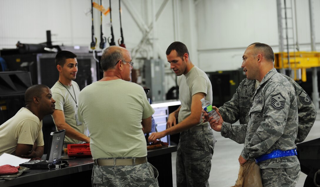Master Sgt. Kelly Moose, right, 1st Aircraft Maintenance Squadron first sergeant, offers water to Airmen working in the sweltering heat as a part of Operation Warm Heart, June 28, 2012, at Langley Air Force Base, Va. The Langley first sergeants kept quiet about the event so they could truly surprise Airmen across the base. (U.S. Air Force photo by Airman 1st Class Austin Harvill/Released) 