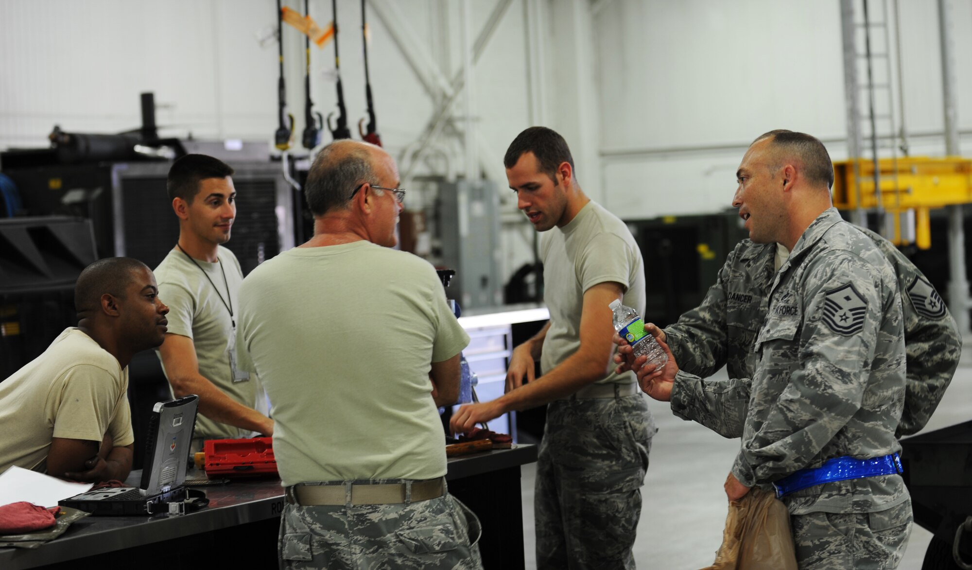 Master Sgt. Kelly Moose, right, 1st Aircraft Maintenance Squadron first sergeant, offers water to Airmen working in the sweltering heat as a part of Operation Warm Heart, June 28, 2012, at Langley Air Force Base, Va. The Langley first sergeants kept quiet about the event so they could truly surprise Airmen across the base. (U.S. Air Force photo by Airman 1st Class Austin Harvill/Released) 