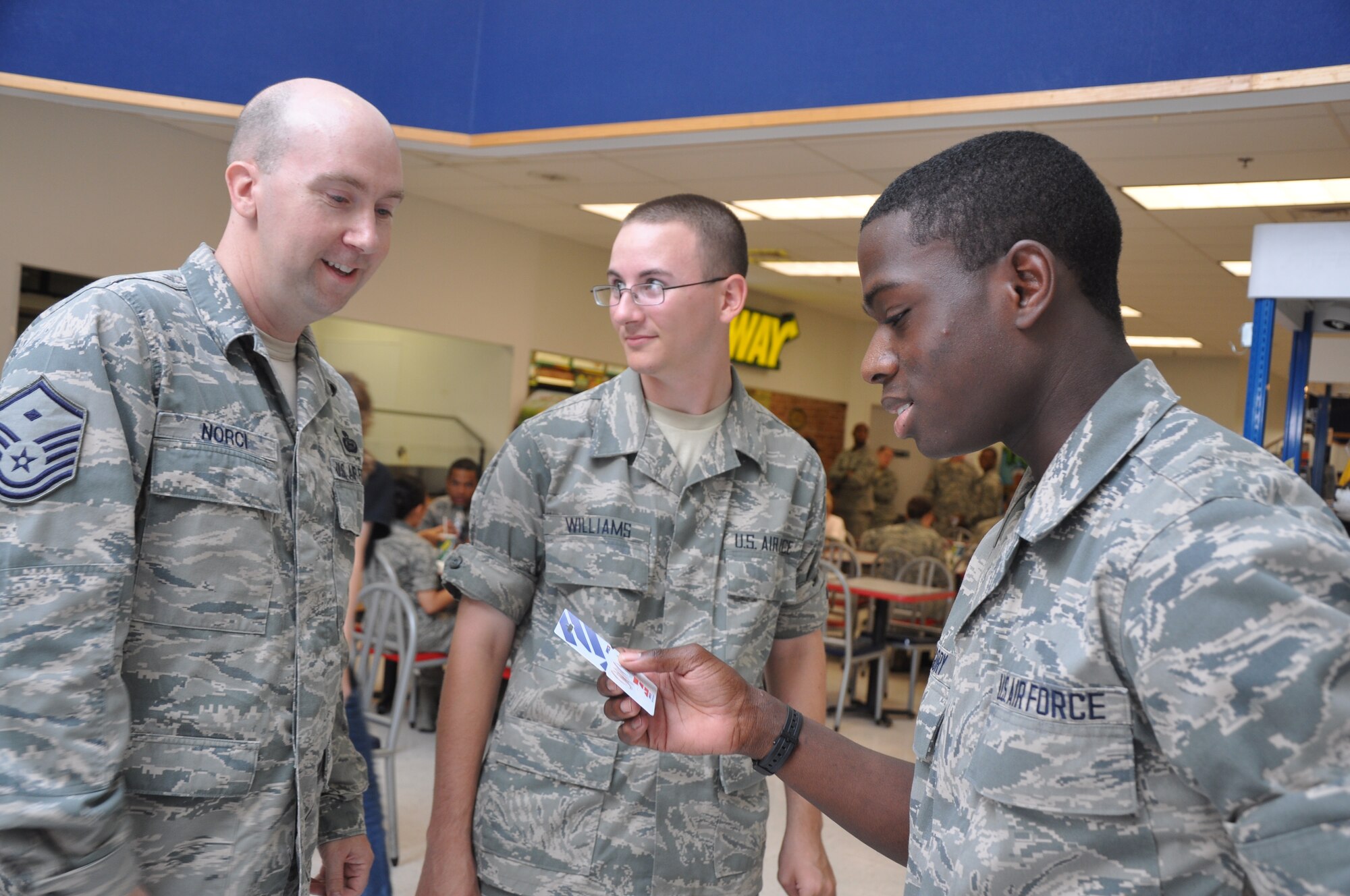 Master Sgt. Christopher Norci, 17th Force Support Squadron first sergeant gives  Airman Gregory Myles and Airman Mason Williams, 316th Training Squadron, $20 AAFES gift cards July 3. Goodfellow first sergeants randomly handed out gift cards totaling $500 to servicemembers. (U.S. Air Force photo/Senior Airman Anne Gathua)