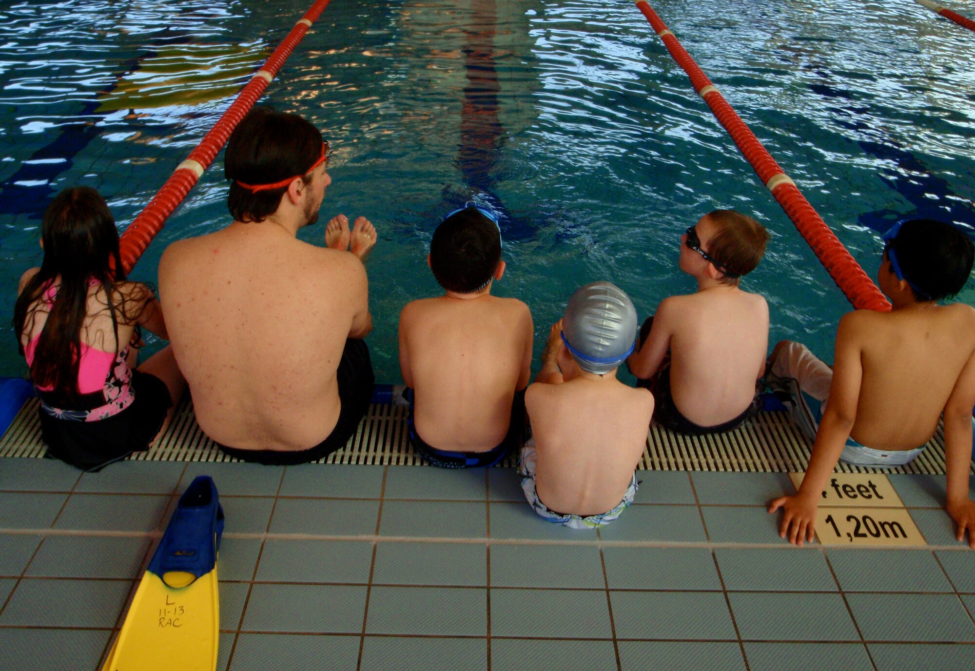 Ben Blixt, water safety instructor, shows his class what their next task is during a swim lesson at the Aquatics Center here June 29. Swim lessons teach children life-long skills of patience, practice, water safety and helps build social skills. (U.S. Air Force photo/Airman 1st Class Hailey Haux)