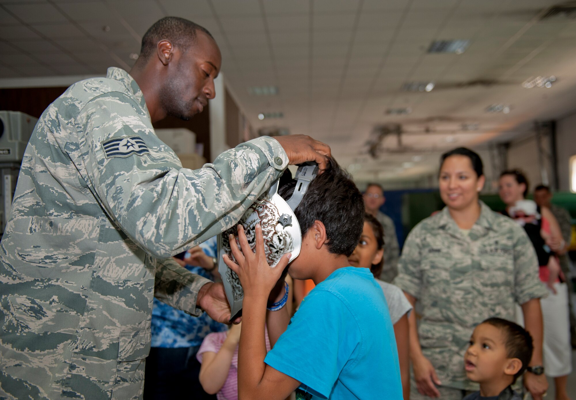 Staff Sgt. Kirk Sheppard, 39th Maintenance Squadron aircraft metals technician, helps a child put on a welding helmet during a squadron tour July 6, 2012, at Incirlik Air Base, Turkey. The metal section of maintenance is primarily used for metals fabrication to create parts for aircrafts. (U.S. Air Force photo by Senior Airman Anthony Sanchelli/Released)