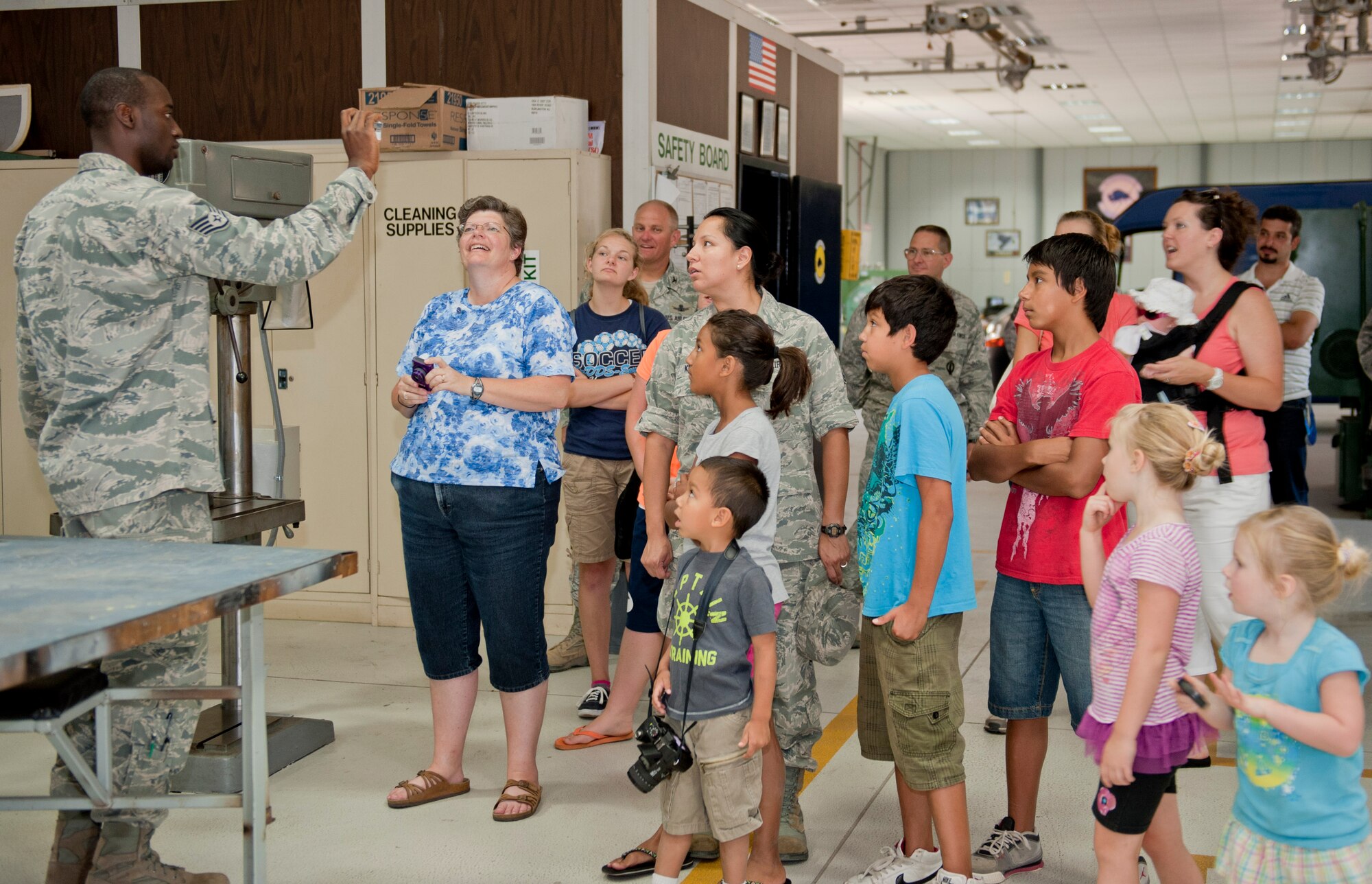 Staff Sgt. Kirk Sheppard, 39th Maintenance Squadron aircraft metals technician, shows spouses and children of 39th Air Base Wing Airmen a piece of equipment during a squadron tour July 6, 2012, at Incirlik Air Base, Turkey. The metal section of maintenance is primarily used for metals fabrication to create parts for aircraft. (U.S. Air Force photo by Senior Airman Anthony Sanchelli/Released)