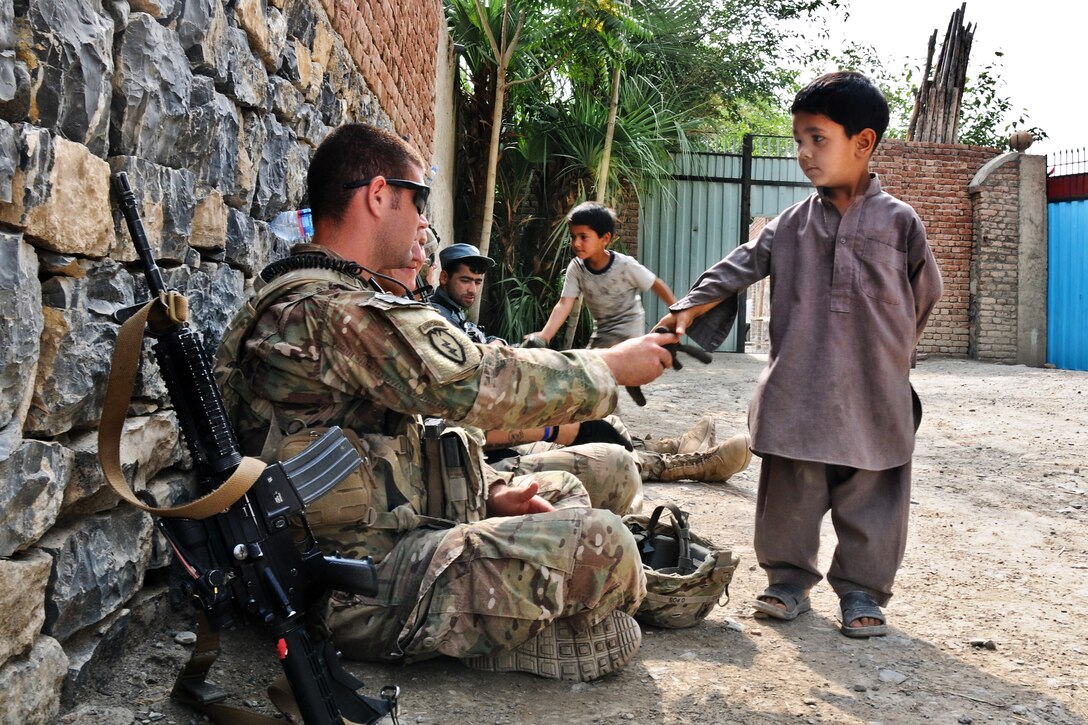 U.S. Army 1st Lt. Greg Lins greets a local Afghan boy inside a qalat of a girls'  school in the village of Mangas in Afghanistan's Khowst province, July 7, 2012. Lins, a platoon leader, is assigned to the 2nd Battalion (Airborne), 377th Field Artillery Regiment. 