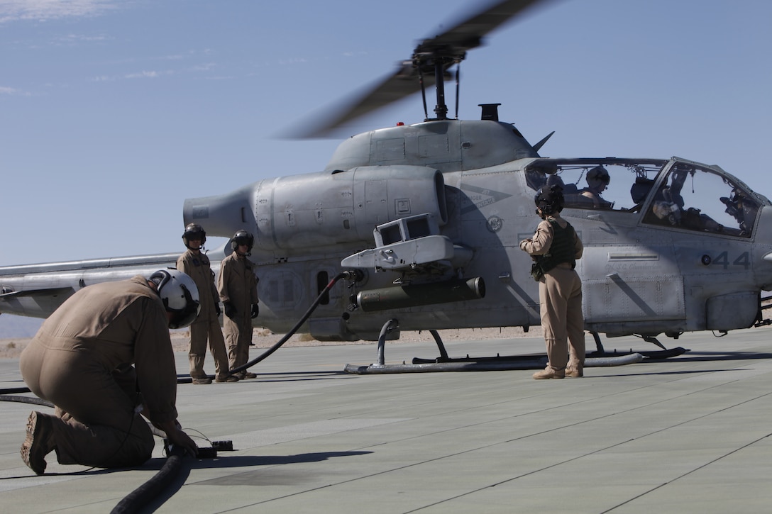 MARINE CORPS AIR GROUND COMBAT CENTER TWENTYNINE PALMS, Calif. - Crew chief Sgt. Greg Farren unkinks the fuel line while Staff Sgt. David Scranton and Sgt. Robert Brensinger - all with Marine Heavy Helicopter Squadron 772 - refuel an AH-1W Super Cobra from the fuel bladder in their CH-53E cargo helicopter at the Strategic Expeditionary Landing Field here during Exercise Javelin Thrust 2012 July 9. Javelin Thrust is an annual large-scale exercise which allows active and reserve Marines and sailors from 38 different states to train together as a seamless Marine Air Ground Task Force. (photo by Master Sgt. Chris W. Cox)