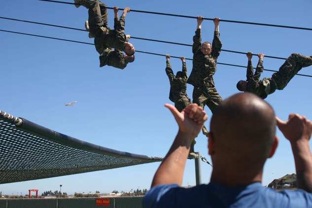 A drill instructor of Company L instructs recruits to change positions while they hold on to a cable above a pool during Confidence Course II June 26 aboard Marine Corps Recruit Depot San Diego. The slide for life is one of the most challenging obstacles of the course because recruits lose themselves in their fear.