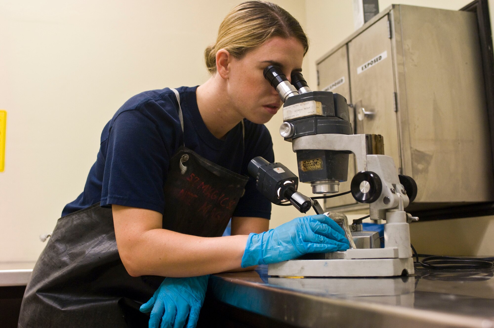 Stephanie Zvonik, 57th MXG CSC, Non-Destructive Inspection Aircraft Mechanic I inspects an aircraft component closely using a microscope. NDI technicians use microscopes to closely inspect materials for faults.  (Air Force Photo by Senior Airman Jack Sanders)