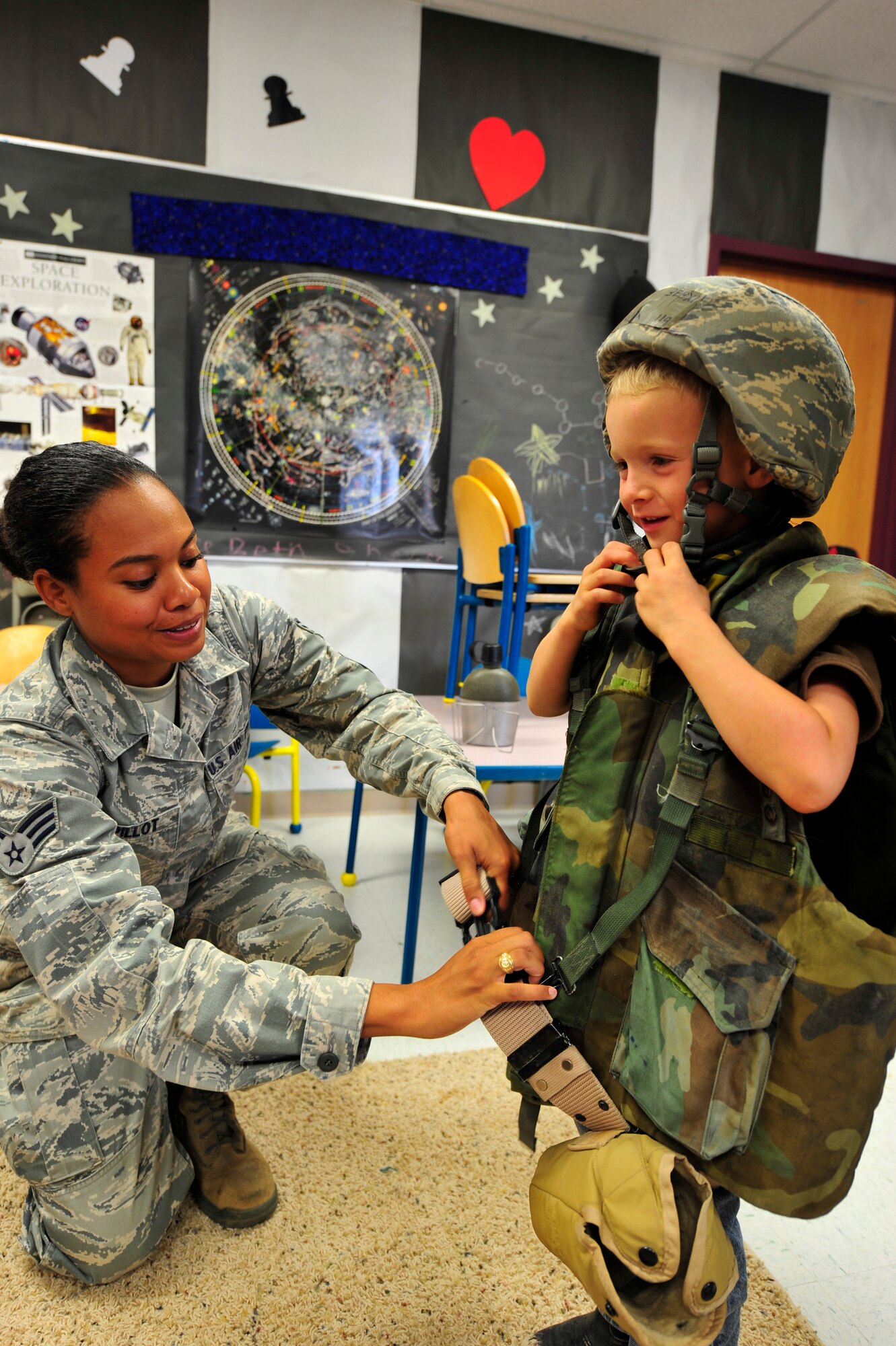 Senior Airman Katia Pillot helps Cale Corbin try on a military vest during the Children's Summer Reading Program at the Ruidoso, N.M. public library, July 9. About 50 kids attended the event which included a scavenger hunt, face painting, camp site setup, survival skills, obstacle course, map and compass reading and other special events. (U.S. Air Force Photo by Senior Airman Martha Whipple/Released)
