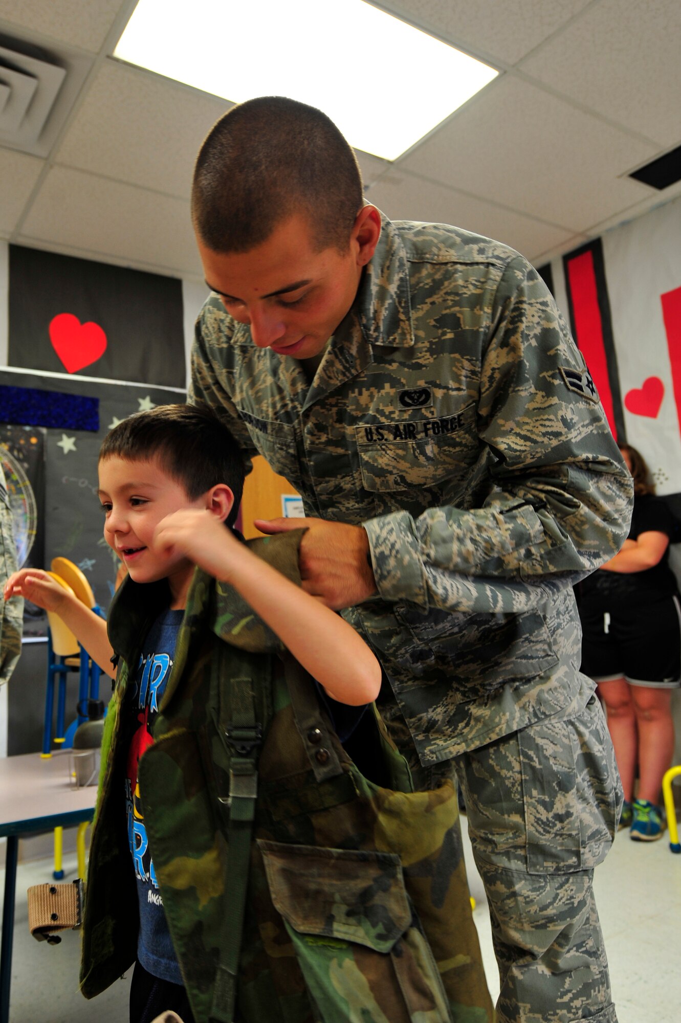 Airman 1st Class Adam Borjon helps Dylan Wells try on a military vest during the Children's Summer Reading Program at the Ruidoso, N.M. public library, July 9. About 50 kids attended the event which included a scavenger hunt, face painting, camp site setup, survival skills, obstacle course, map and compass reading and other special events. (U.S. Air Force Photo by Senior Airman Martha Whipple/Released)