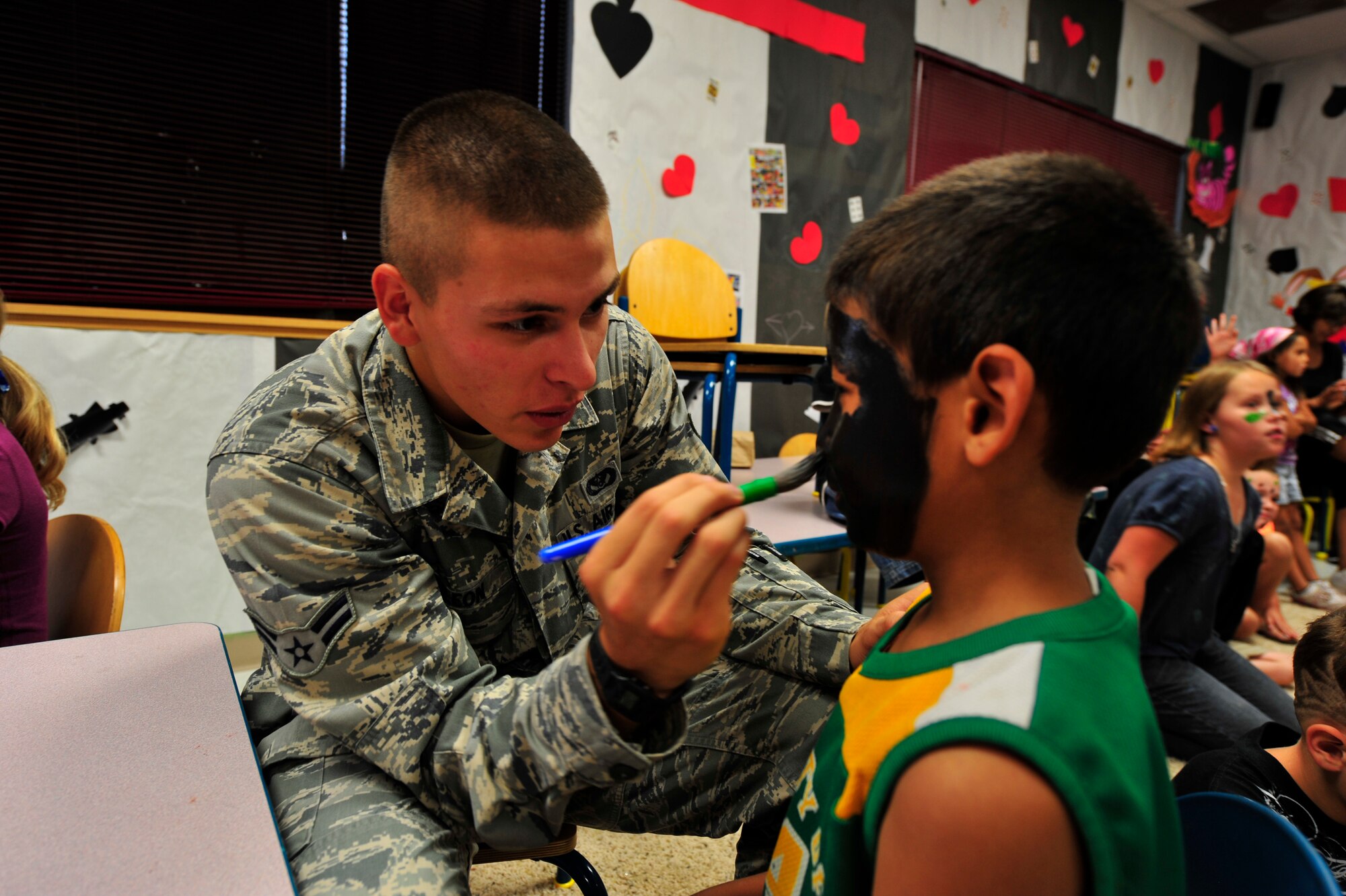 Airman 1st Class Jorge DeLeon paints Devon Brazil's face during the Children's Summer Reading Program at the Ruidoso, N.M. public library, July 9. DeLeon was one of five Team Holloman Airmen who volunteered for the military/survival week of the reading program. About 50 kids attended the event which included a scavenger hunt, face painting, camp site setup, survival skills, obstacle course, map and compass reading and other special events. (U.S. Air Force Photo by Senior Airman Martha Whipple/Released)