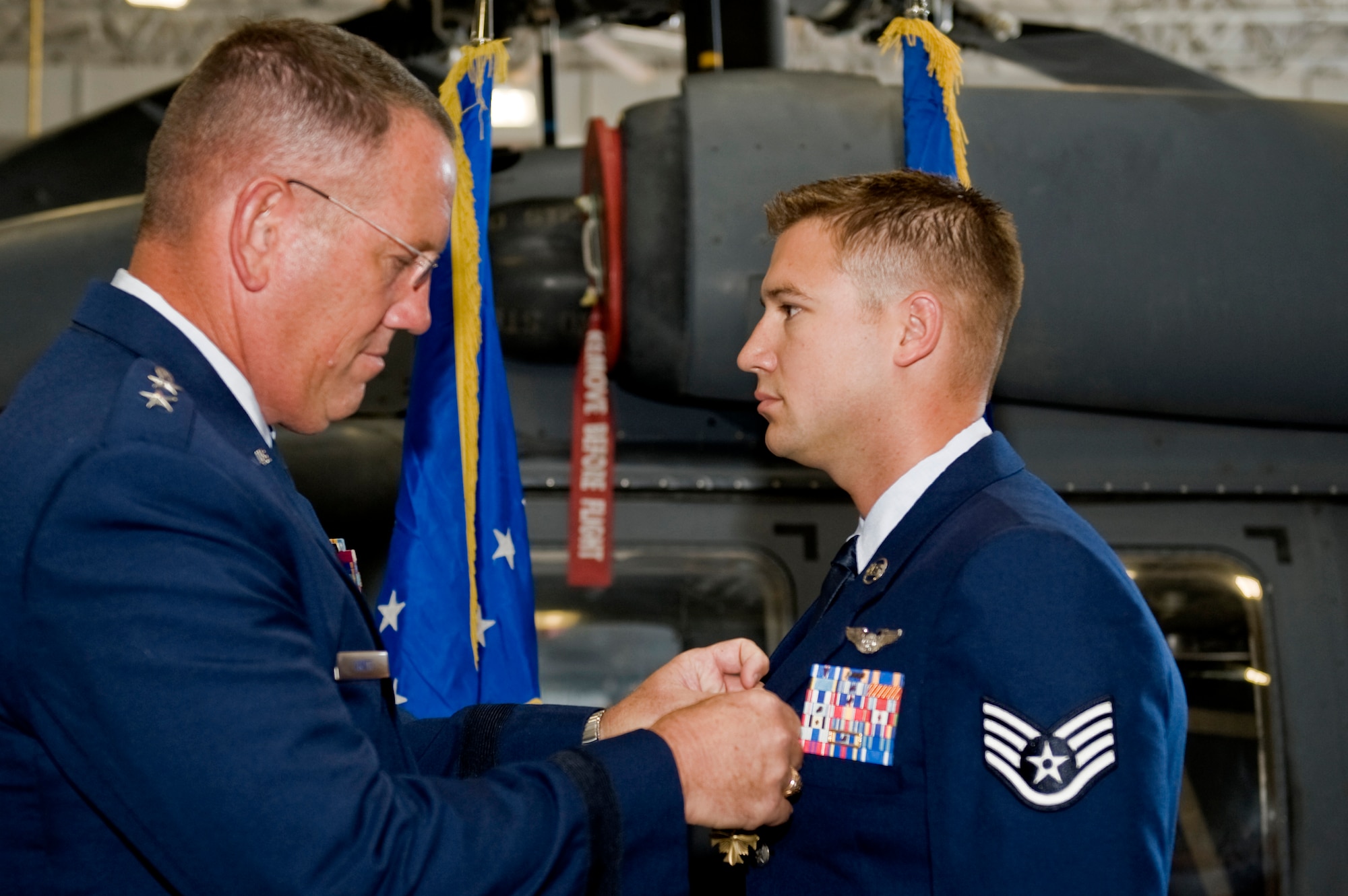 U.S. Air Force Maj. Gen. Bill Hyatt, U.S. Air Force Warfare Center commander, presents the Distinguished Flying Cross with Valor to Staff Sgt.Justin Tite, 88th Test and Evaluation Squadron aerial gunner, July 9, 2012, at Nellis Air Force Base, Nev. Tite received the prestigious medal for life saving combat operations in Afghanistan where he identified and eliminated enemy combatants, enabling the rescue of injured soldiers. (U.S. Air Force photo by Staff Sgt. William P.Coleman)