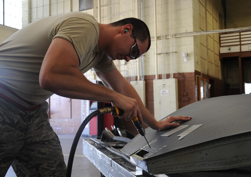Senior Airman Colton McCall, 2nd Maintenance Squadron Fabrication Flight aircraft structural maintenance journeyman, uses a pneumatic drill to perform a permanent repair on the cracked skin of a wheel-well door on a B-52H Stratofortress bomber on Barksdale Air Force Base, La., July 10. Repairing skin cracks is vital in maintaining the structural integrity of the aircraft. Without proper structural integrity, the bomber would not be able to safely complete its mission. (U.S. Air Force photo/ Senior Airman Sean Martin)(RELEASED)