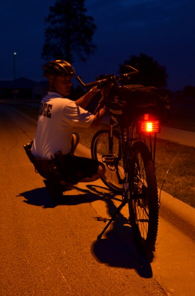 Airmen 1st Class Cody Weaver, 7th Security Forces Squadron, prepares his bicycle for night patrol July 9, 2012, at Dyess Air Force Base, Texas. From May to September, officers in groups of two ride throughout Dyess assisting with situations that may occur. Dyess base housing has paths that patrol cars aren’t able to navigate, but the bike patrol is able to ensure they’re secured. The patrols not only keep the neighborhoods safe, they also help build rapport with residents. (U.S. Air Force photo by Airman 1st Class Nancy Kasberg/Released)