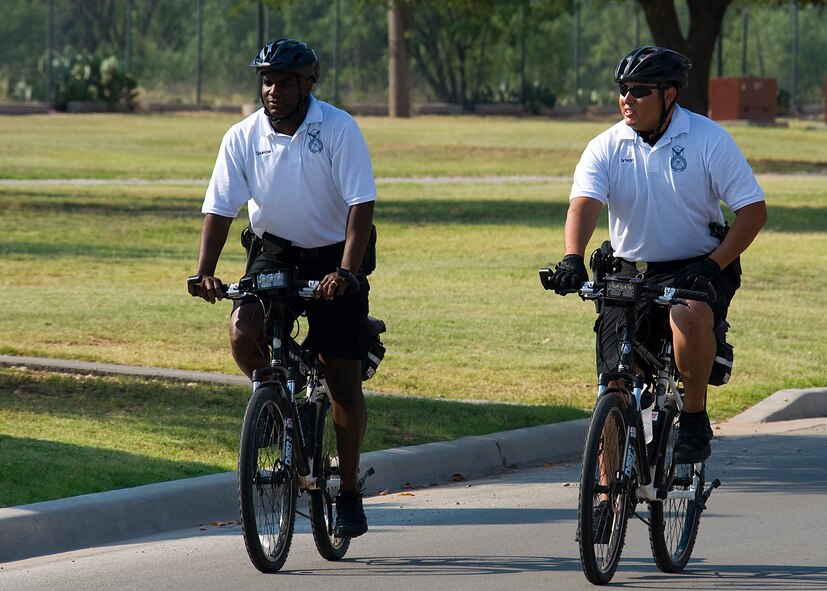 Officer James Sparrow, left, and Officer Luis Ortega, 7th Security Forces Squadron, patrol base housing June 28, 2012, at Dyess Air Force Base, Texas. From May to September, officers in groups of two ride throughout Dyess assisting with situations that may occur. Dyess base housing has paths that patrol cars aren’t able to navigate, but the bike patrol is able to ensure they’re secured. The patrols not only keep the neighborhoods safe, they also help build rapport with residents. (U.S. Air Force photo by Airman 1st Class Damon Kasberg/Released)
